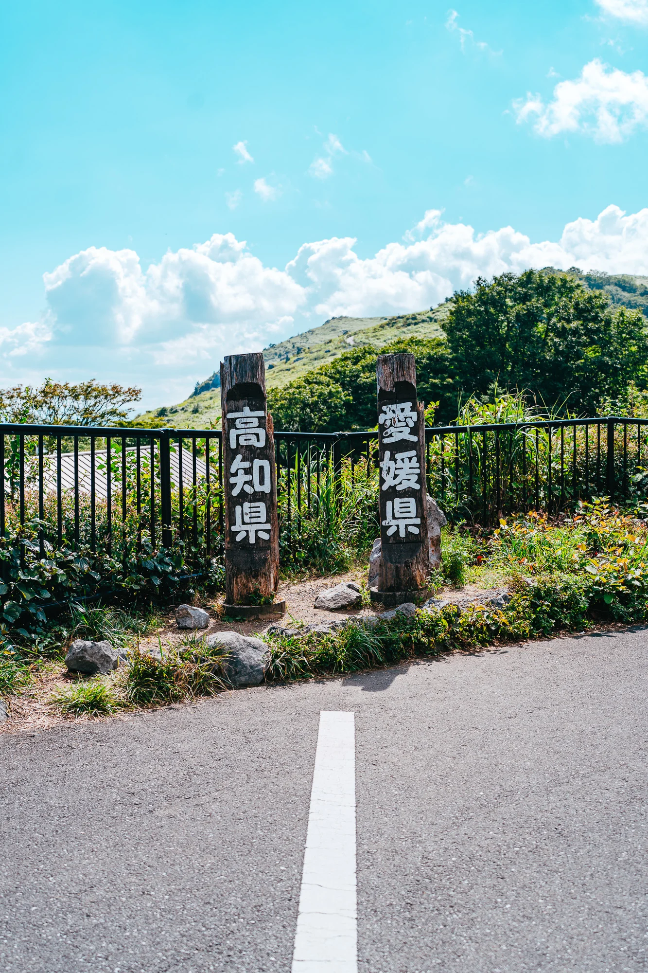 道路をまたいで立つ高知県と愛媛県の県境の標柱